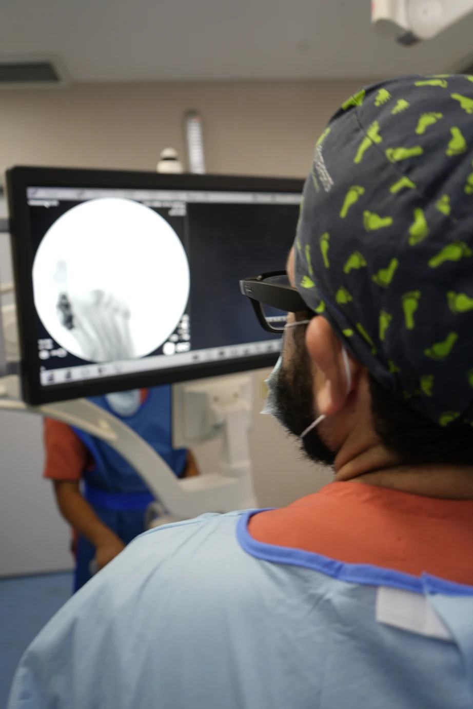 El Dr. Isaac Pacheco revisa el control radiológico de un pie durante una cirugía